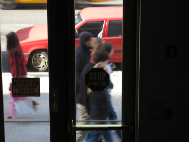 A woman, loaded with bags, passes five people.