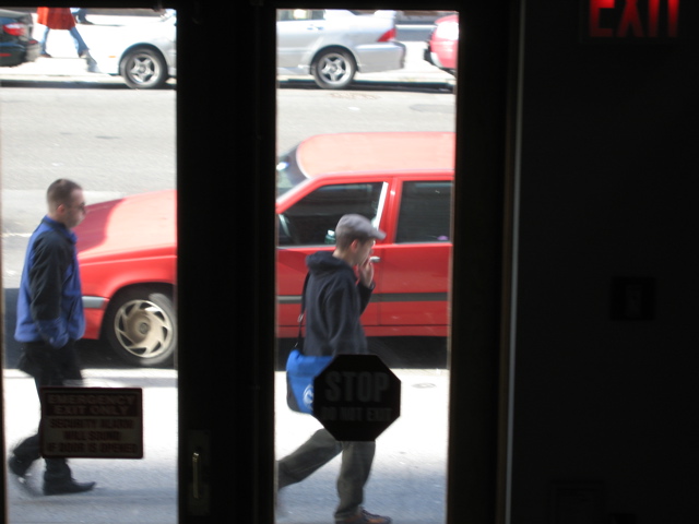 A man smoking, ahead of a man shuffling slowly north.