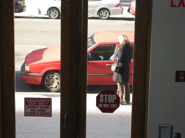 The woman looks at the car as if she is preparing to enter.