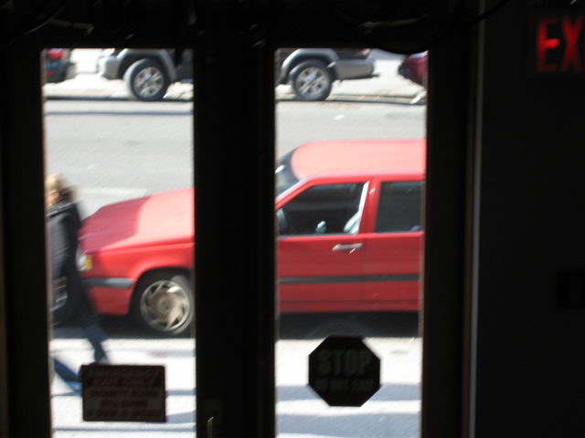 A woman hurriedly passes the red car