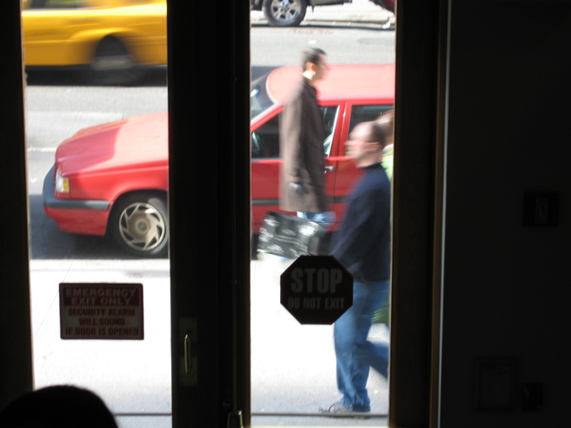 A man with a black shopping bag passes two people; a cab; a friend's head (bottom left)