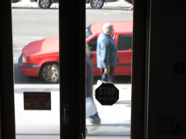 A man with gloves holding a shopping bag passing a woman