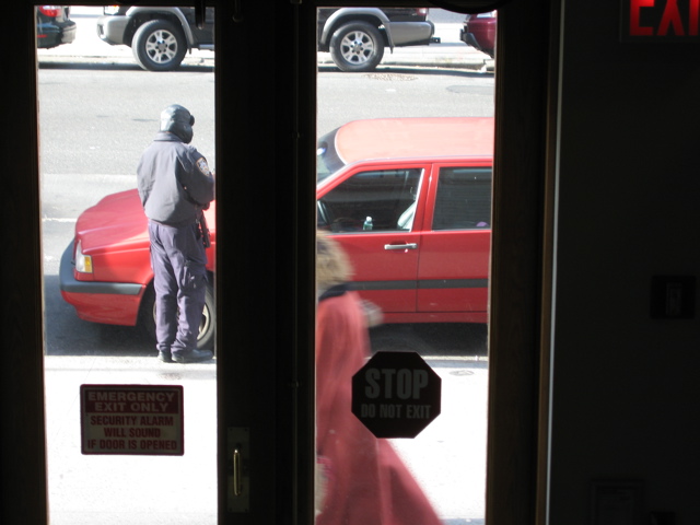 A woman in red walks past the policeman at the car