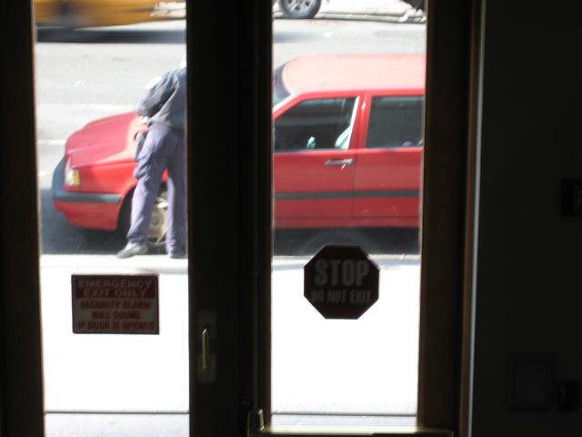 A cab passes in the background as the policeman puts the ticket on the car
