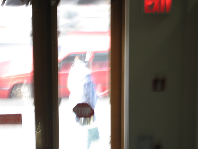 A very blurry picture of a woman walking past with a purse
