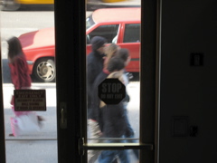 A woman, loaded with bags, passes five people.