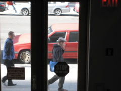 A man smoking, ahead of a man shuffling slowly north.