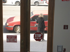A blonde woman stops at the car. Is it her car?