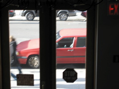 A woman hurriedly passes the red car