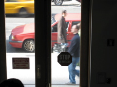 A man with a black shopping bag passes two people; a cab; a friend's head (bottom left)