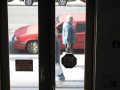 A man with gloves holding a shopping bag passing a woman