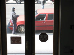A policeman approaches the red car; A man jay-walks