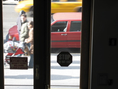 A couple with a stroller pass the policeman; A cab passes in the background