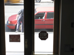 A cab passes in the background as the policeman puts the ticket on the car