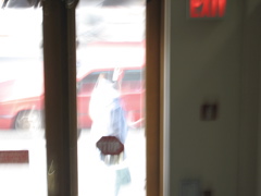 A very blurry picture of a woman walking past with a purse