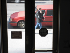 A woman with a purple scarf talks on her cell phone, as the SUV in the background has left its parking sopt