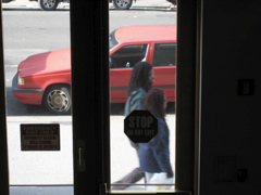 A white car pulls into the background parking space, as two people with long hair walk by